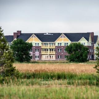 A colorful residential building surrounded by trees and grasslands.