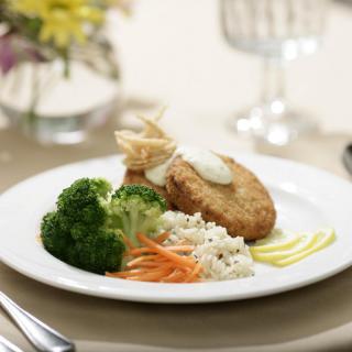 A gourmet meal with chicken, rice, broccoli, and garnishes on a white plate.