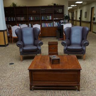 A cozy seating arrangement featuring two armchairs and a wooden coffee table in a library setting.