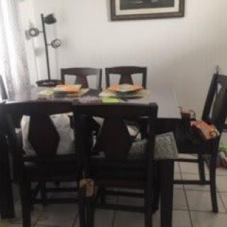 A dining area with a wooden table set and chairs, accompanied by a standing lamp.