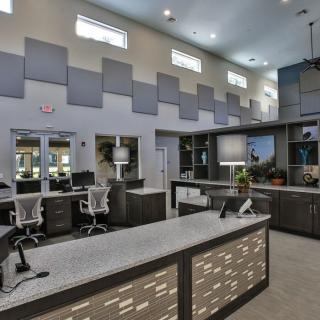 A modern office reception area with desks, chairs, computers, and stylish lighting.