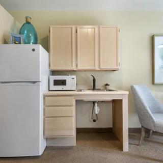 A compact kitchenette featuring a refrigerator, microwave, sink, and cabinets.