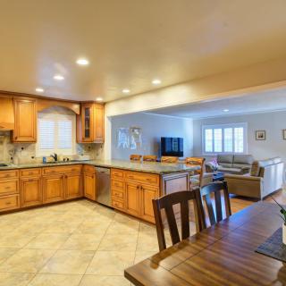 A spacious open floor plan featuring a kitchen with wooden cabinets, a dining table, and an adjacent living room.