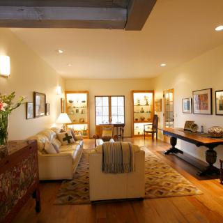 A warmly lit living room featuring a comfortable sofa, coffee table, and elegant artwork on the walls.