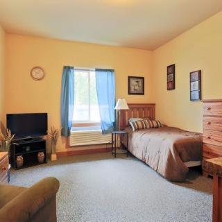 A cozy bedroom with a single bed, television, and wooden furniture.