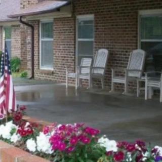 A cozy porch with rocking chairs and an American flag, adorned with colorful flowers.