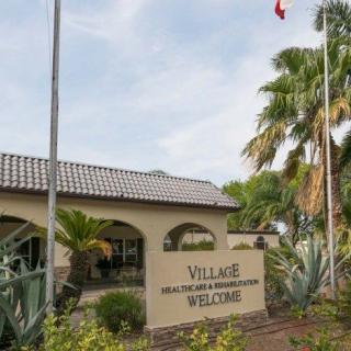 Entrance to a community center with tropical landscaping and flags.