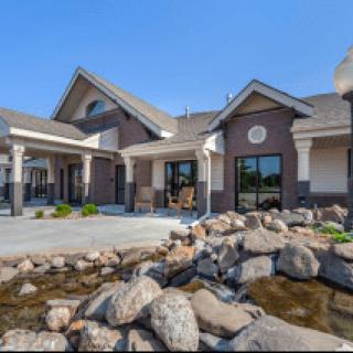 A beautiful residential house with a landscaped front yard featuring rocks and a small pond.