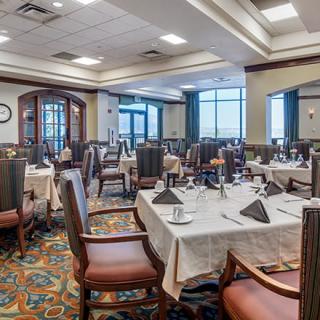 An elegantly set restaurant dining room with multiple tables ready for guests.