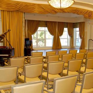 An elegant conference room with arranged seating and a grand piano by the windows.