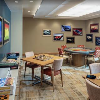A modern game room featuring a chessboard and poker table, decorated with vibrant artwork.