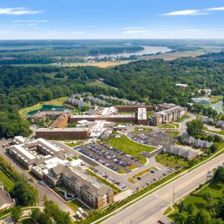 An aerial view of a large complex with buildings, parking lots, and surrounding greenery.