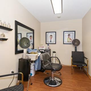 A cozy hair salon with styling chairs and framed pictures on the wall.
