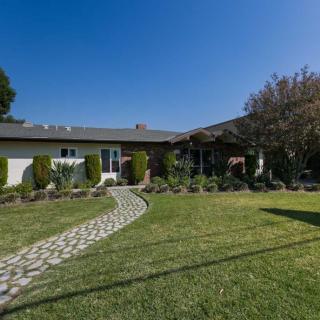 A charming suburban house with a well-maintained lawn and garden under a clear blue sky.