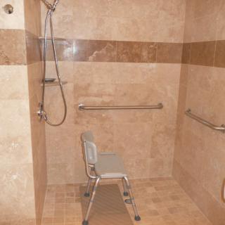 A walk-in shower with a shower chair and grab bars for accessibility.