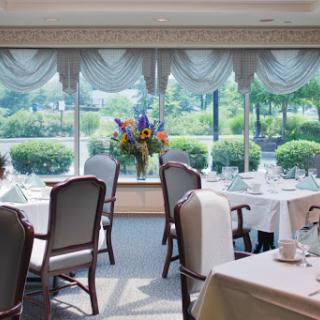 A beautifully arranged dining room with elegant decor, featuring flowers and a scenic view.