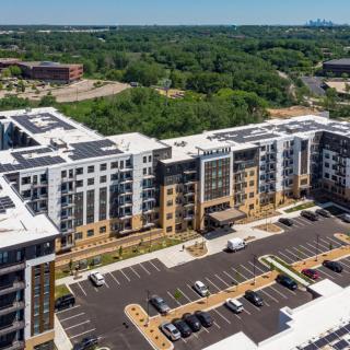 Aerial view of a modern apartment complex with surrounding greenery.