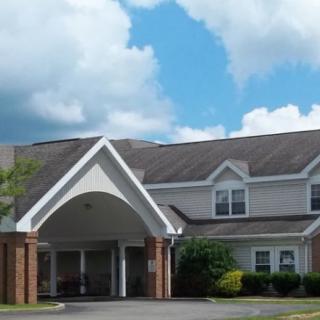 A suburban residential building with a large entrance and a partly cloudy sky in the background.