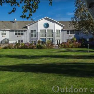 A residential building with a well-maintained lawn and garden in front.