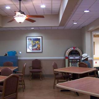 A cozy dining area featuring wooden tables and chairs, a ceiling fan, and a jukebox for entertainment.