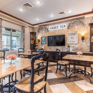 A cozy restaurant interior with neatly arranged tables and chairs, featuring wall art and a television for a welcoming dining experience.