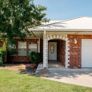 A brick residential house with a garage and front lawn.