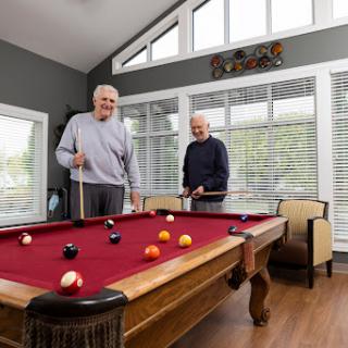 Two men enjoying a friendly game of pool in a bright and inviting game room.