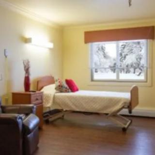A bright and cozy hospital room with a bed and a chair next to a large window.