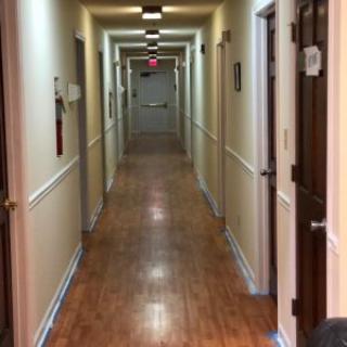 A view down a well-lit hallway featuring multiple doors on either side.