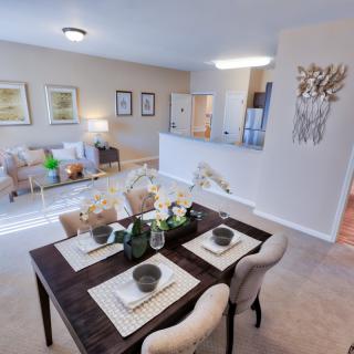 A modern open-concept dining and living area with elegant decor and a fully set table.