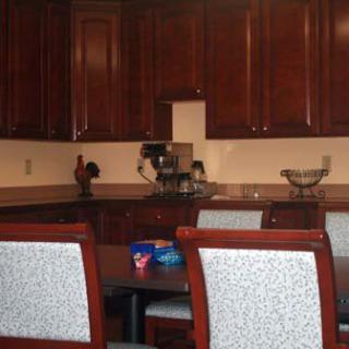 A modern kitchen with dark wooden cabinets, a dining table, and chairs.