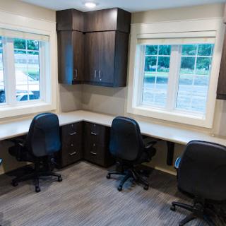 A bright and modern office space featuring two workstations with ergonomic chairs and ample natural light.