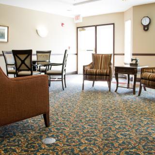 A cozy living room with chairs, a table, and patterned carpet.