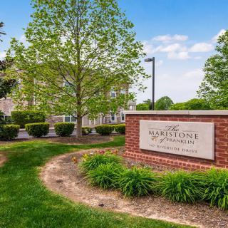 Entrance sign for a residential apartment complex surrounded by well-maintained landscaping and greenery.