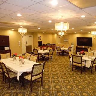 An elegant dining room with neatly arranged tables and chairs, illuminated by chandeliers.
