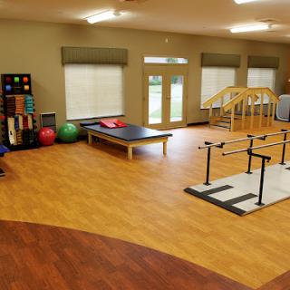 A spacious physical therapy room equipped with exercise equipment and various therapy tools.