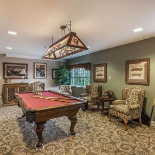 A cozy billiard room with a pool table, traditional decor, and comfortable seating.