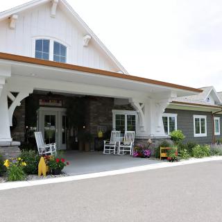 A welcoming entrance with rocking chairs and flowers adorning the porch.