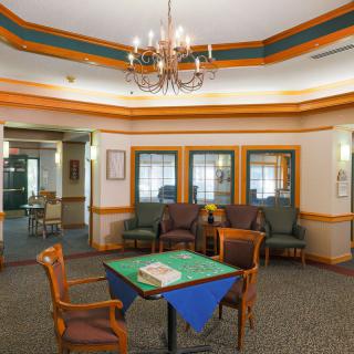 A cozy room with a chandelier, seating area, and a table covered with a blue cloth.