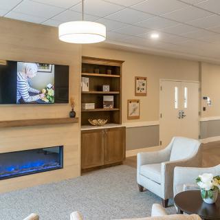 A cozy living room with modern decor, featuring a wall-mounted television, an electric fireplace, and comfortable seating.