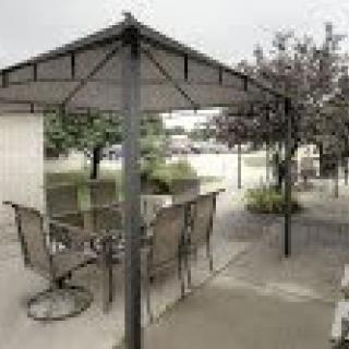 Outdoor gazebo with chairs and a table on a paved surface.