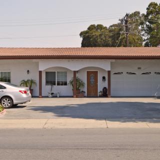 A suburban house with a driveway and garage, featuring a parked car in front.