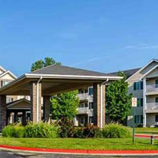 A residential apartment complex with a covered entrance and landscaped surroundings.