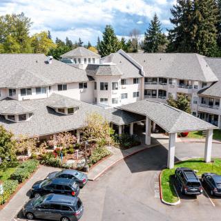 Aerial view of a residential building complex with parked cars and surrounding trees.