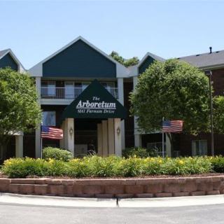 The entrance to an apartment complex surrounded by trees and landscaping.