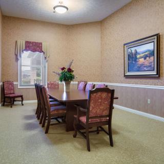 A well-decorated dining room with a wooden table and chairs, complemented by a wall painting and window.
