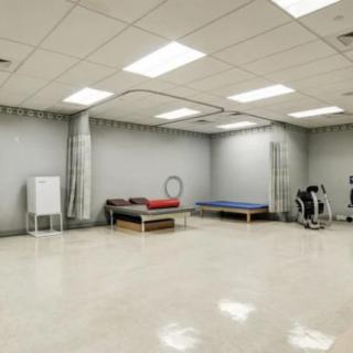 A spacious physical therapy room equipped with treatment beds and exercise equipment.