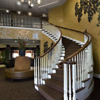 A grand, sweeping staircase in an elegantly decorated lobby with a chandelier.
