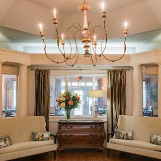 Elegant living room with a central chandelier, twin sofas, and floral decor.