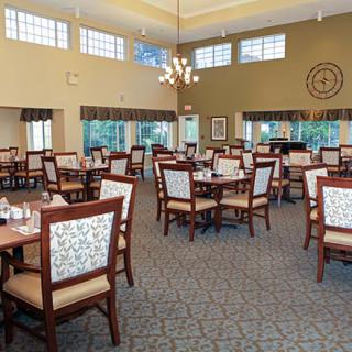 A spacious dining area with neatly arranged tables and chairs, featuring elegant lighting and decor.
